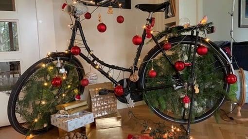 A bike decorated with baubles and leaves.