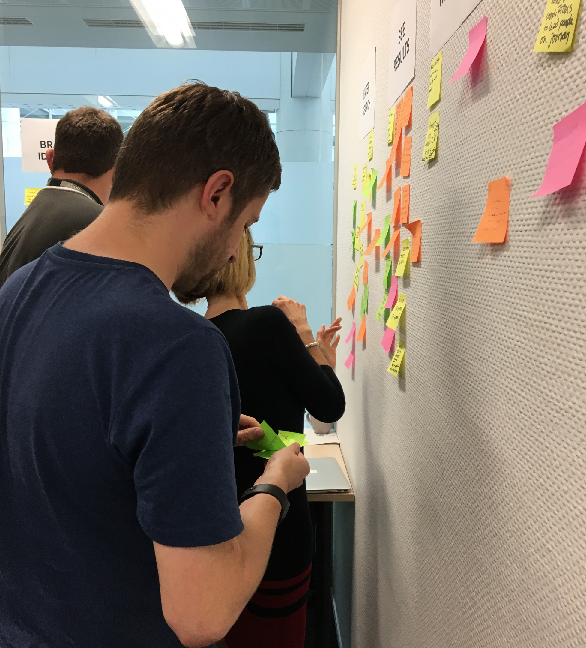People looking at post-it notes on a wall