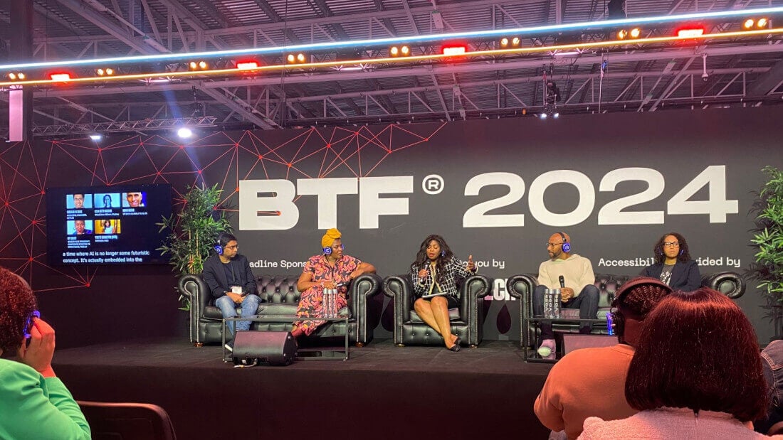 The panel at Black Tech Fest 2024 sitting in front of a banner with the conference's name.